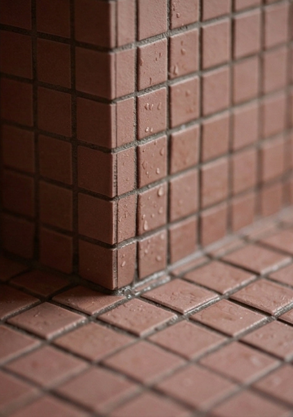 Pink Granite Meshed Clay Tile by Clay Imports forming a textured corner and floor with water droplets.
