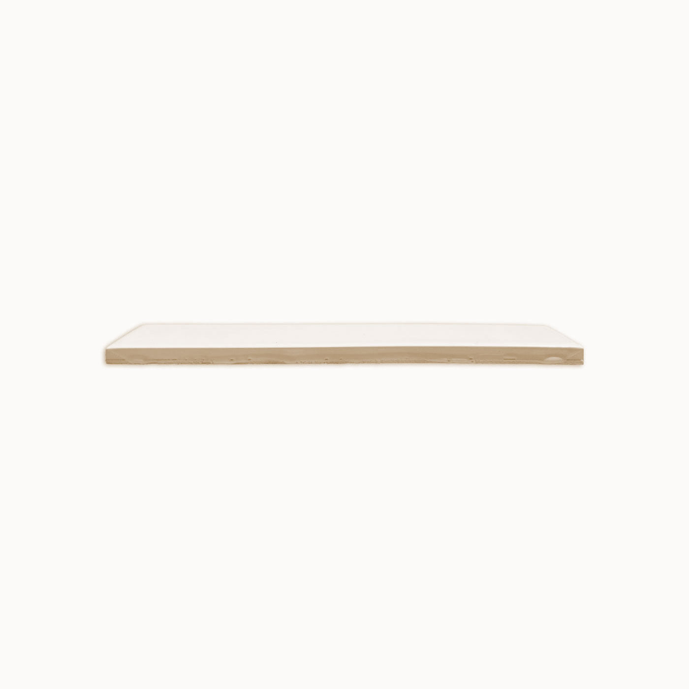A Fossil Gloss 2x12 solid tile by Clay Imports, displaying its raw beige side from a horizontal view.