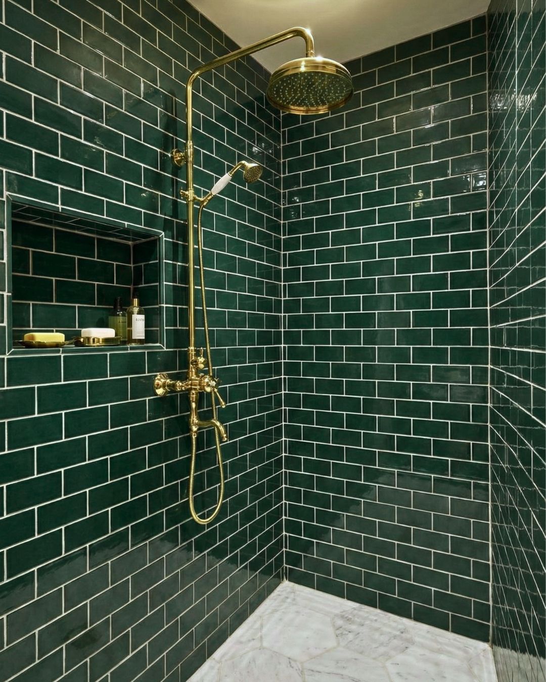 Green 2x6 clay subway tiles by Clay Imports installed in a shower with prominent gold fixtures and white grout.