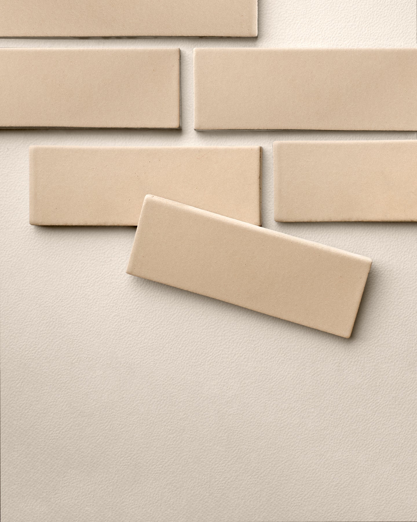 Beige rectangular clay tiles by Clay Imports, showing a matte finish on a textured background, one tile askew.