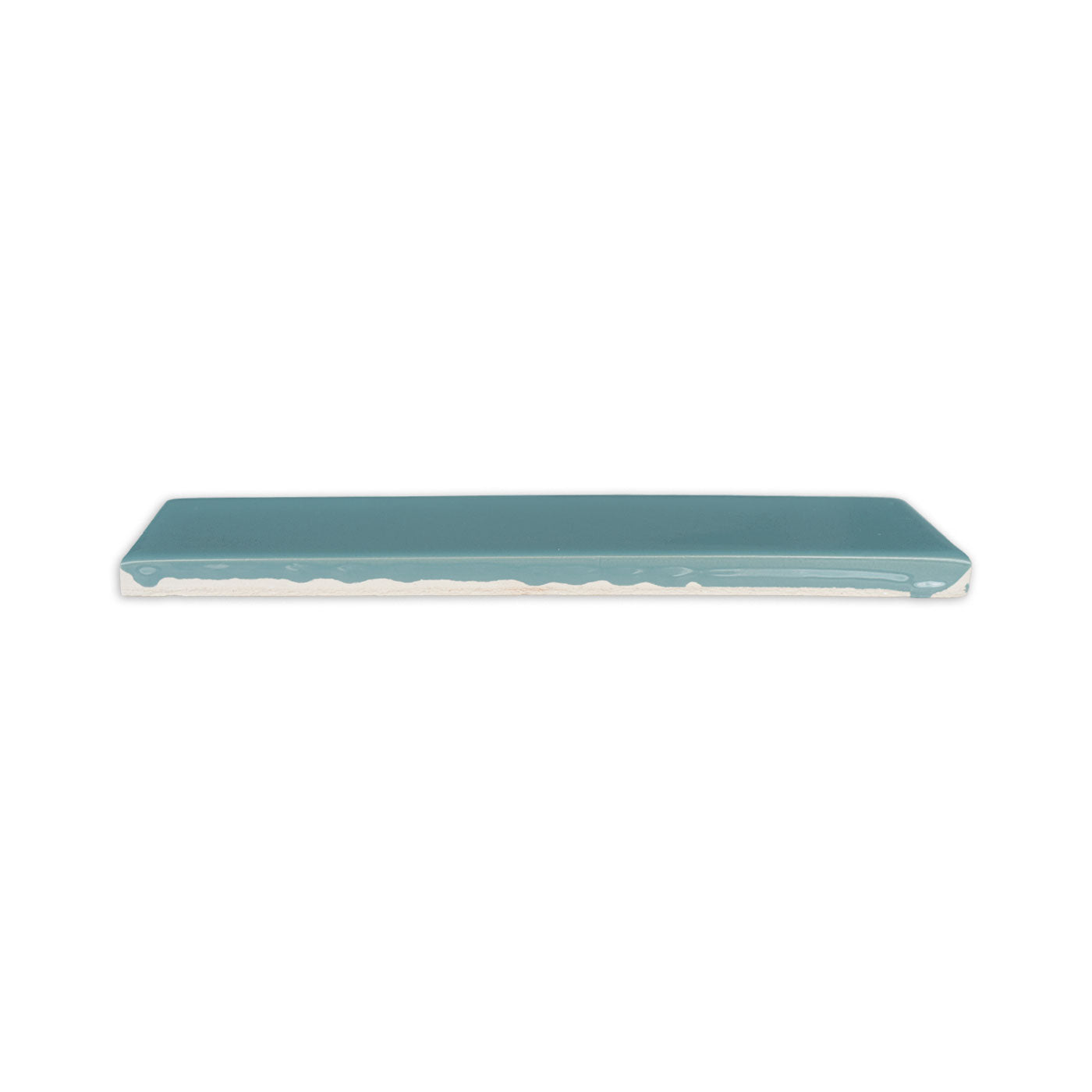 Teal glossy 2x8 solid tile from Clay Imports, viewed from the side showing its unglazed base.
