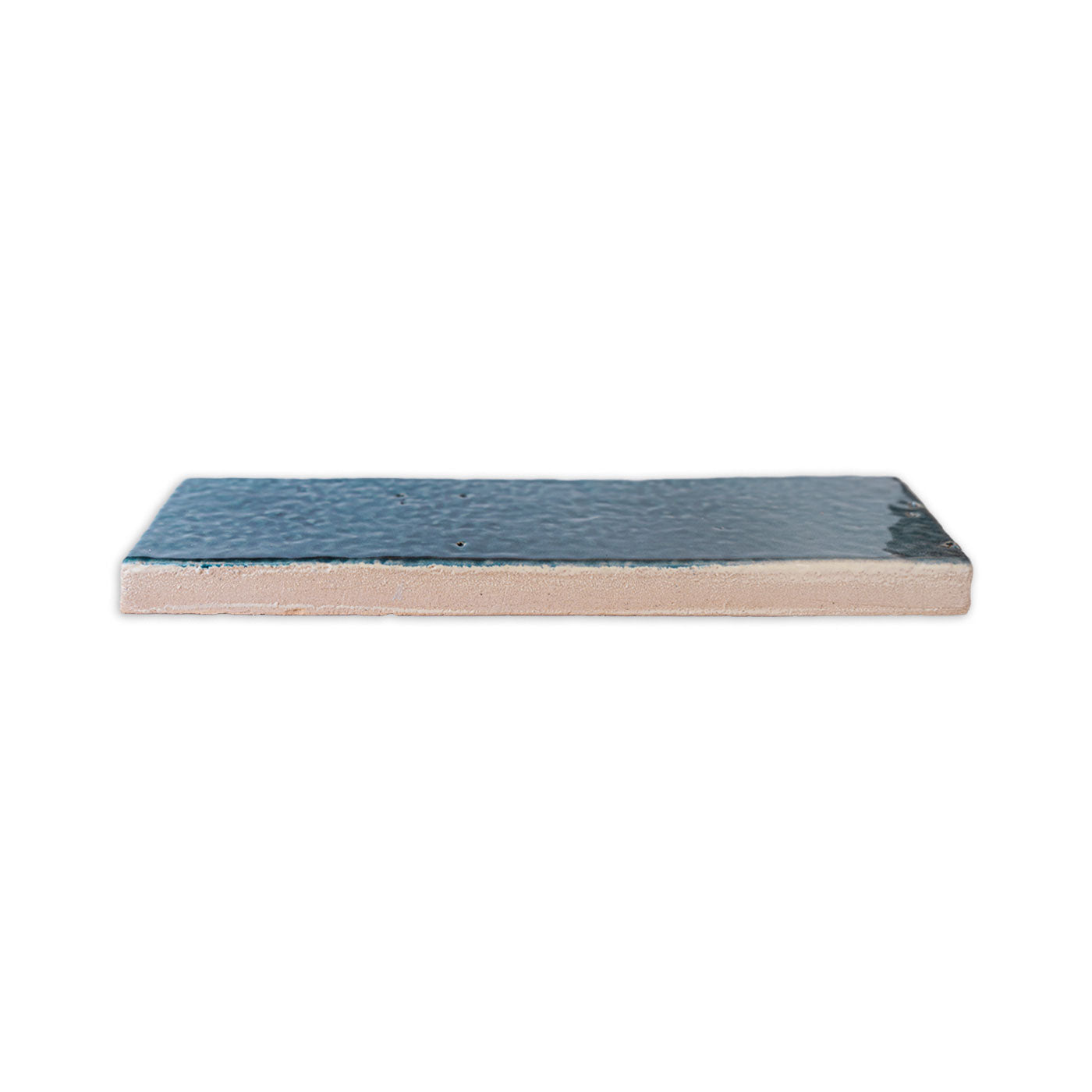 Botanical Teal glazed thin brick by Clay Imports, with a textured surface, shown in a side profile view revealing its tan unglazed edge.