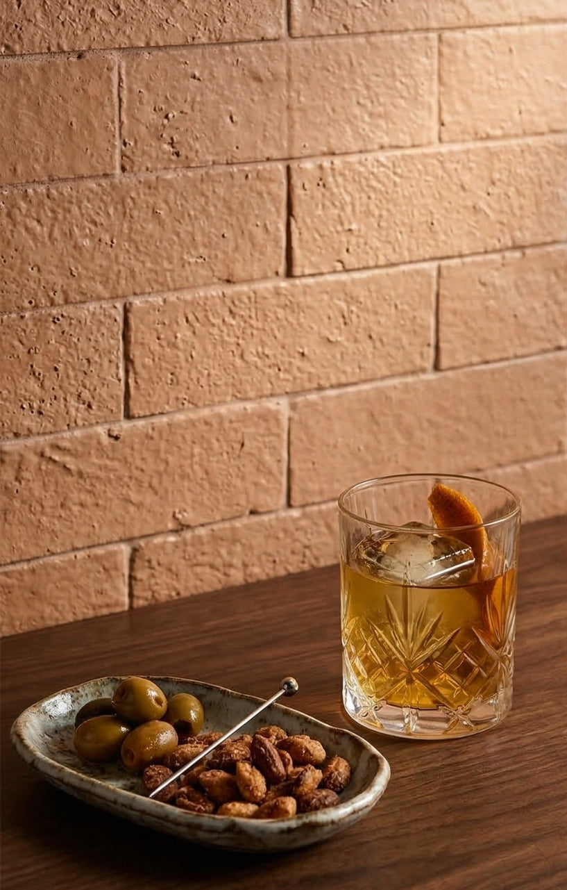 Glazed Thin Brick in Tequila 2.5x8 by Clay Imports, featuring a rough texture behind a cocktail and snacks.