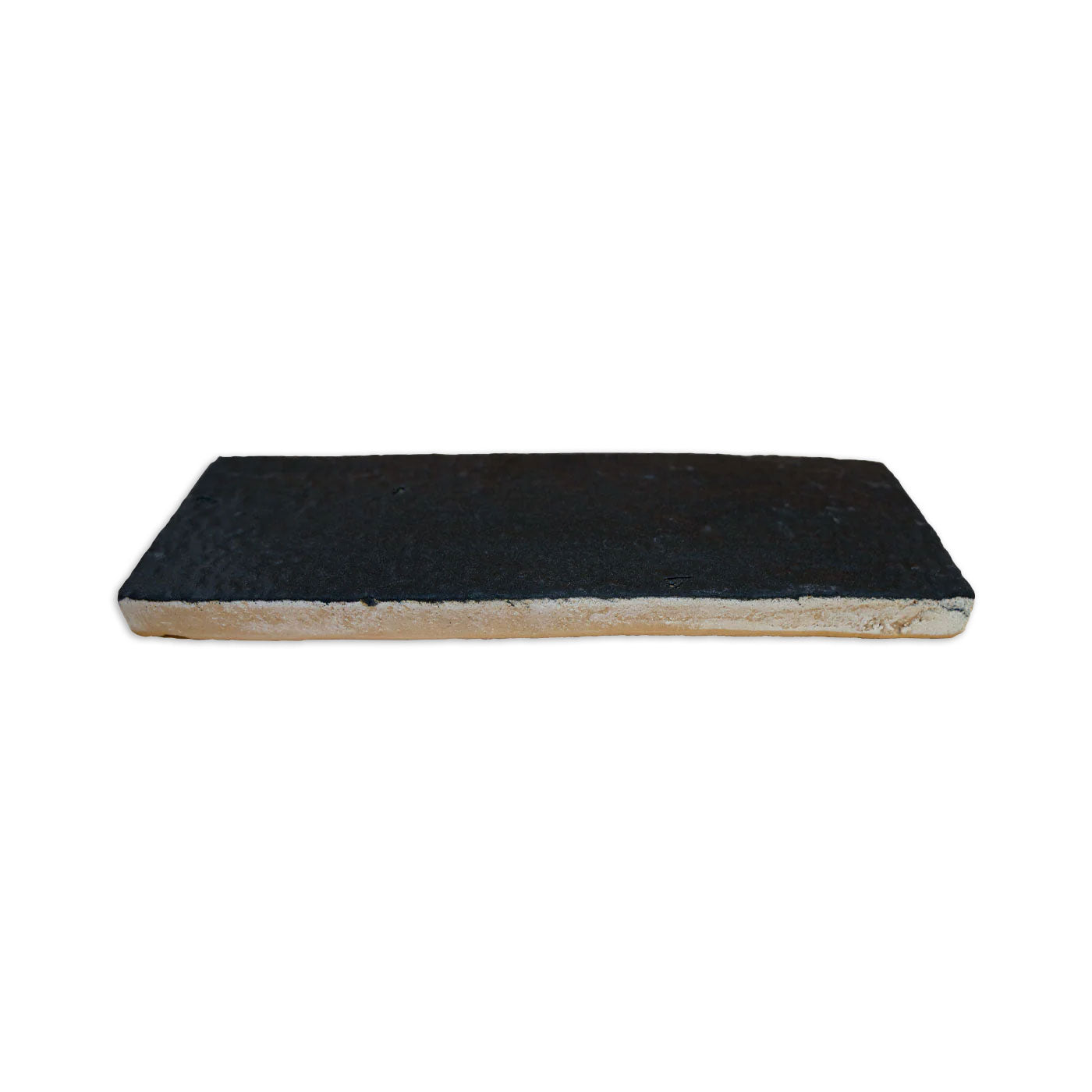 Black Suede 2.5x8 Glazed Thin Brick Sample by Clay Imports, showing a textured black top and light beige sides in a side view.