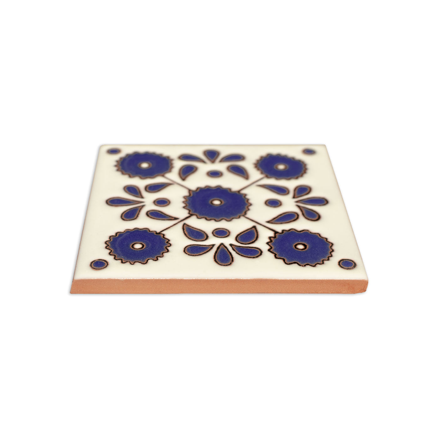 White ceramic Relief Talavera tile by Clay Imports with a blue floral pattern and terracotta side, angled view.