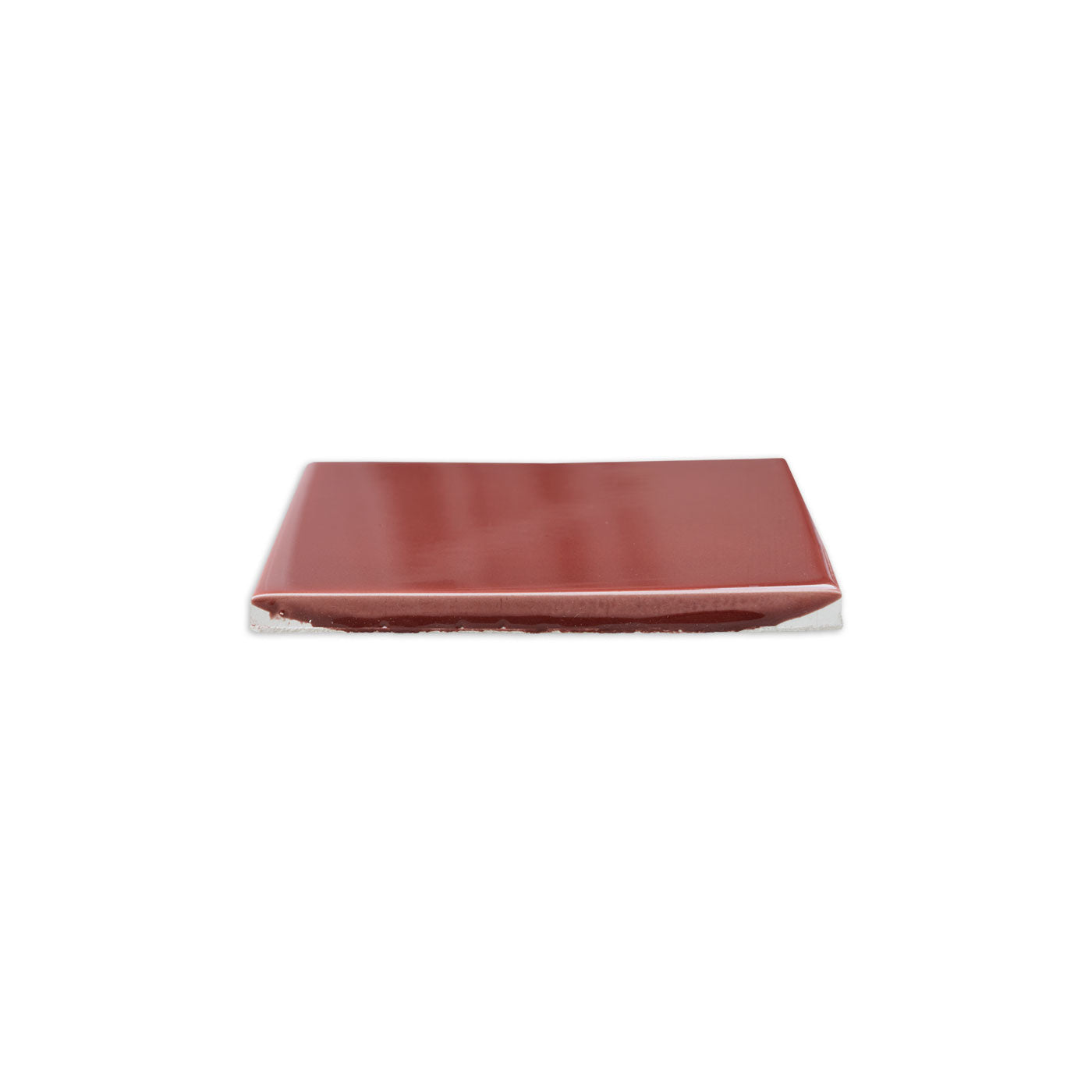 Burgundy gloss solid tile by Clay Imports, viewed from the side, revealing its reflective surface and rough, unglazed bottom edge.