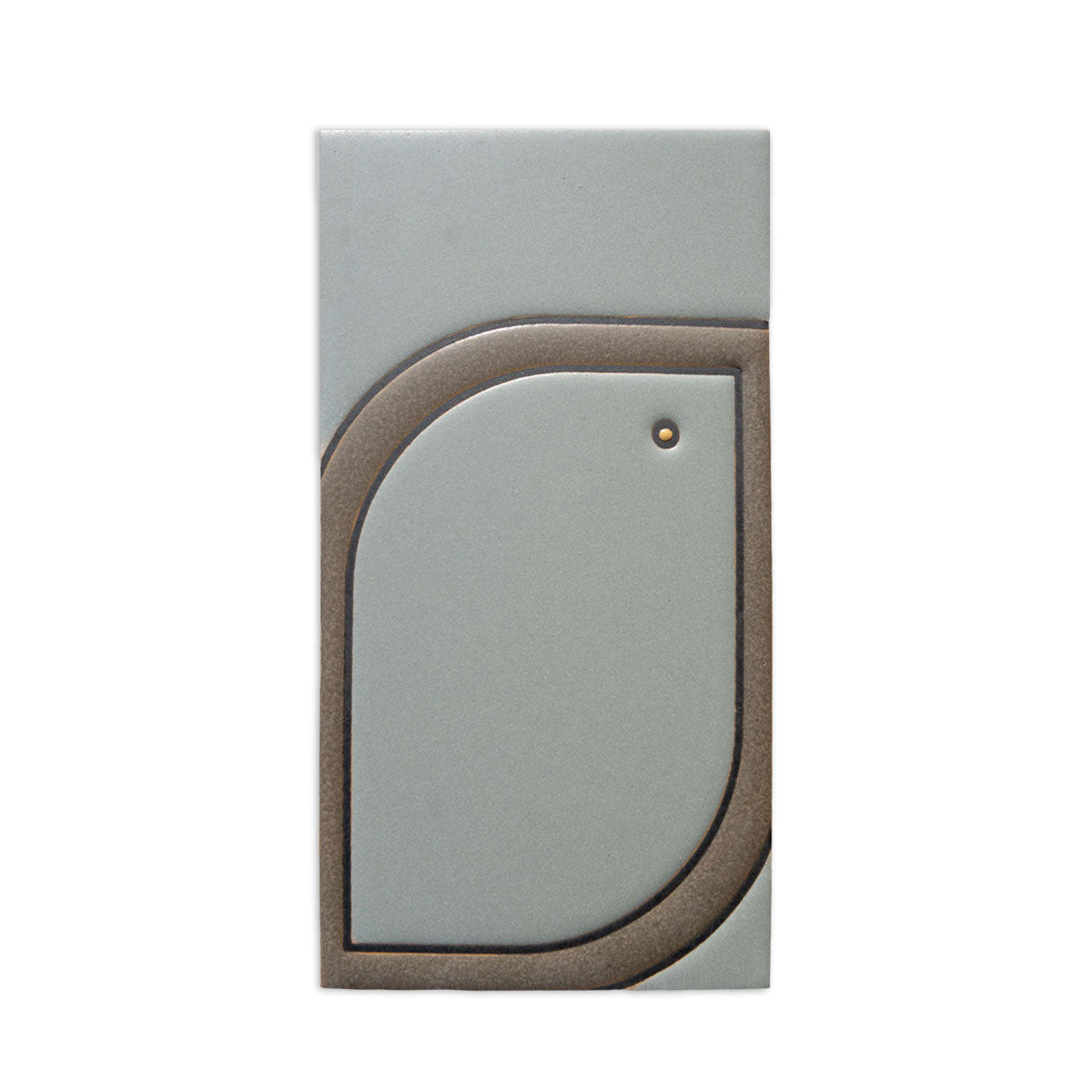 Greenish-gray rectangular tile sample by Clay Imports, featuring a raised bronze leaf pattern and a small dot.