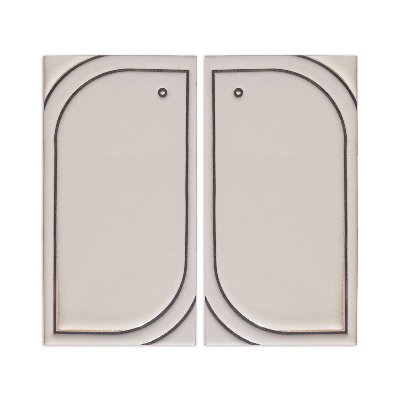 Two light beige ceramic tile samples by Clay Imports, each featuring a mirrored, etched rounded rectangle design and a small hole.
