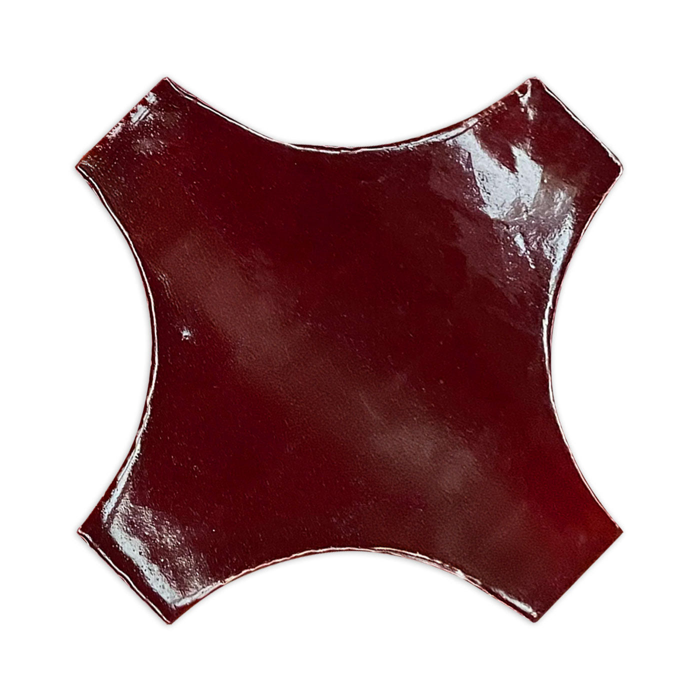 Oxblood red tile sample from Clay Imports, featuring a glossy finish and distinctive quatrefoil shape.