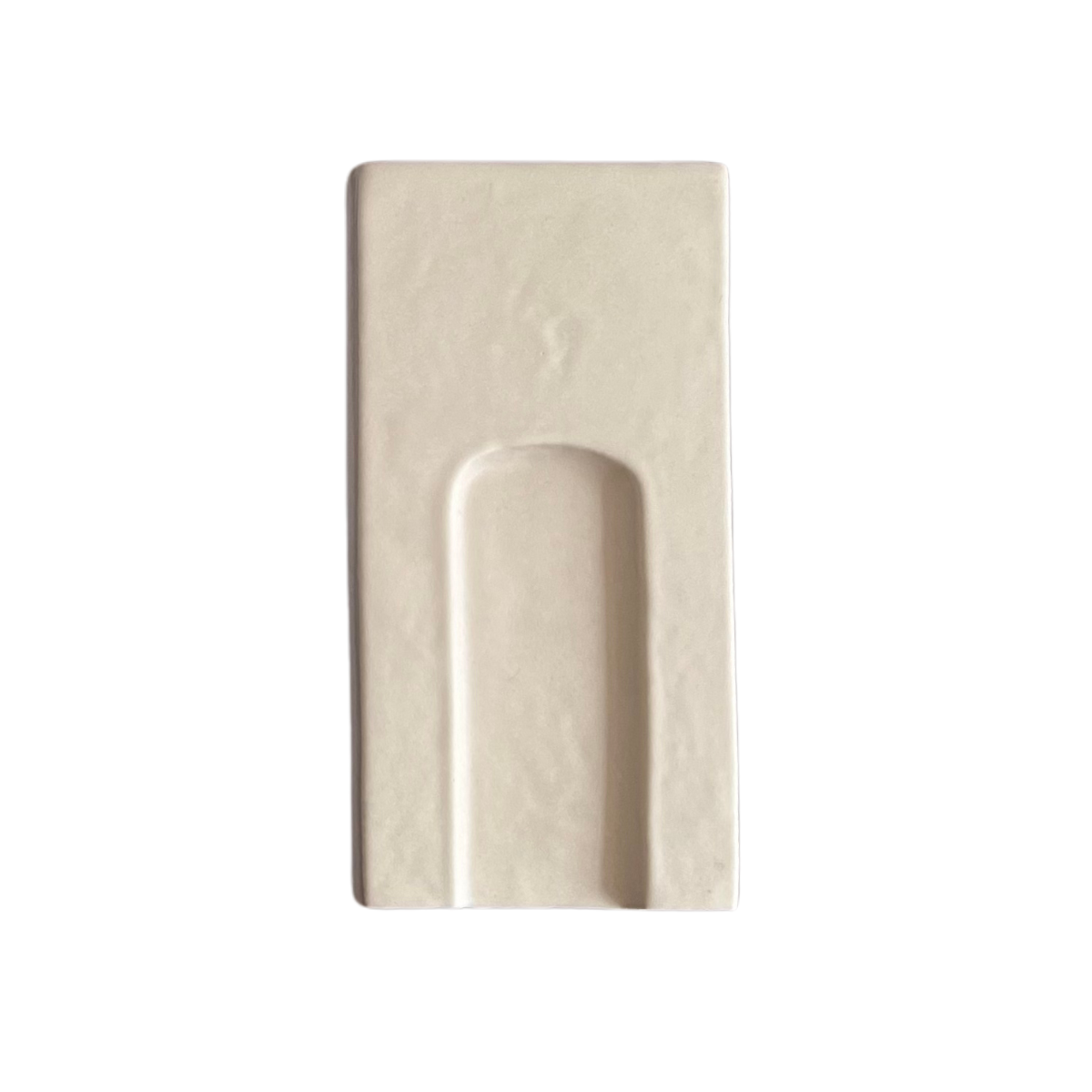Off-white tile sample by Clay Imports, a rectangular piece with a recessed arch design.