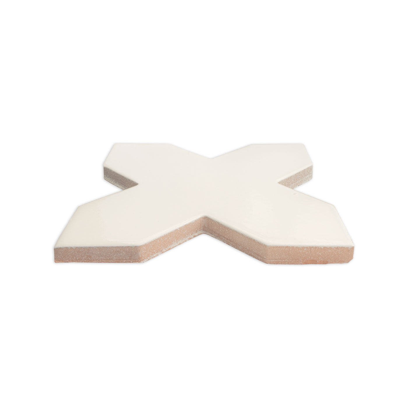 Creamy white cross-shaped tile by Clay Imports with a glossy top and natural bisque edges, viewed from a low angle.