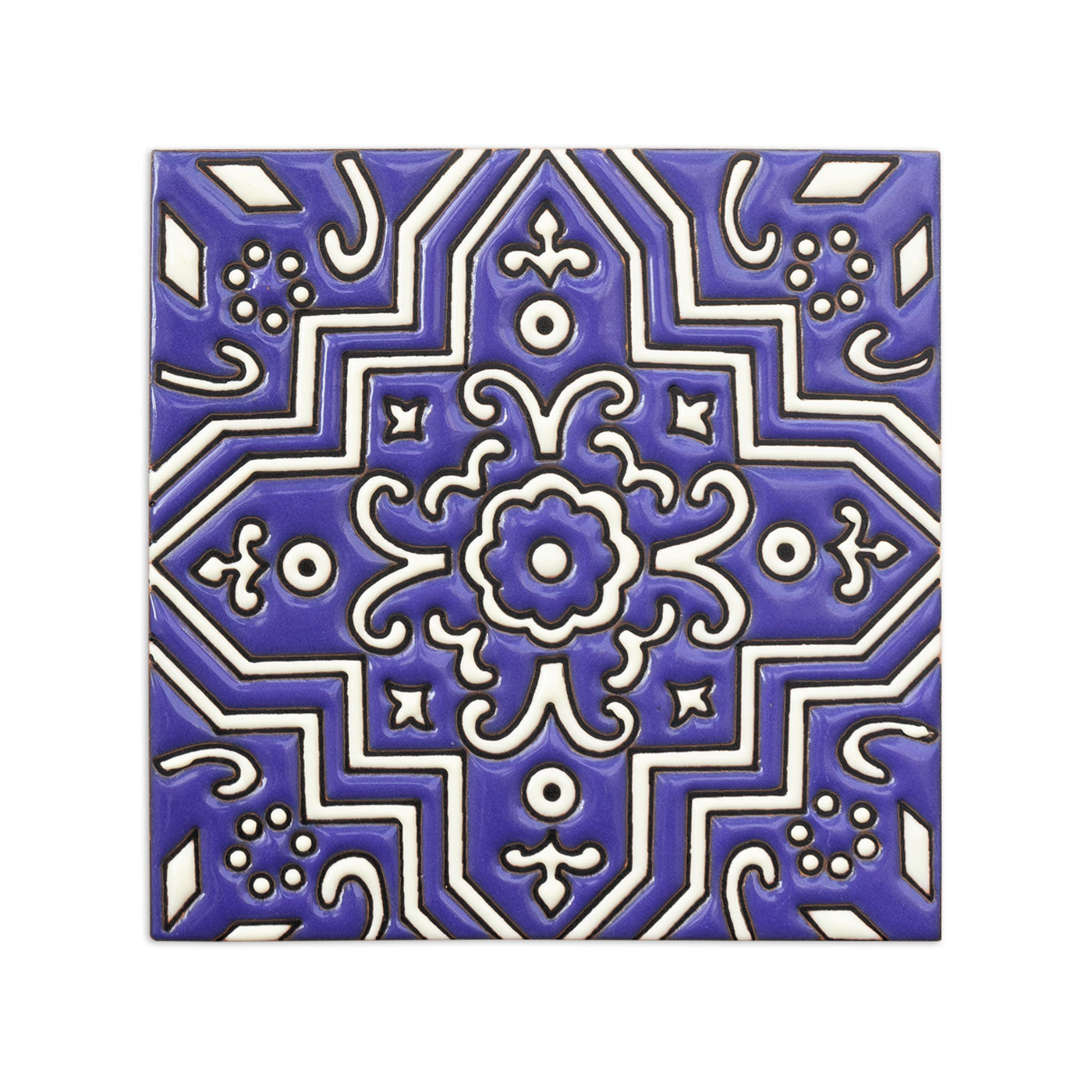 Blue and white ceramic sample tile by Clay Imports with a raised ornate symmetrical floral pattern.