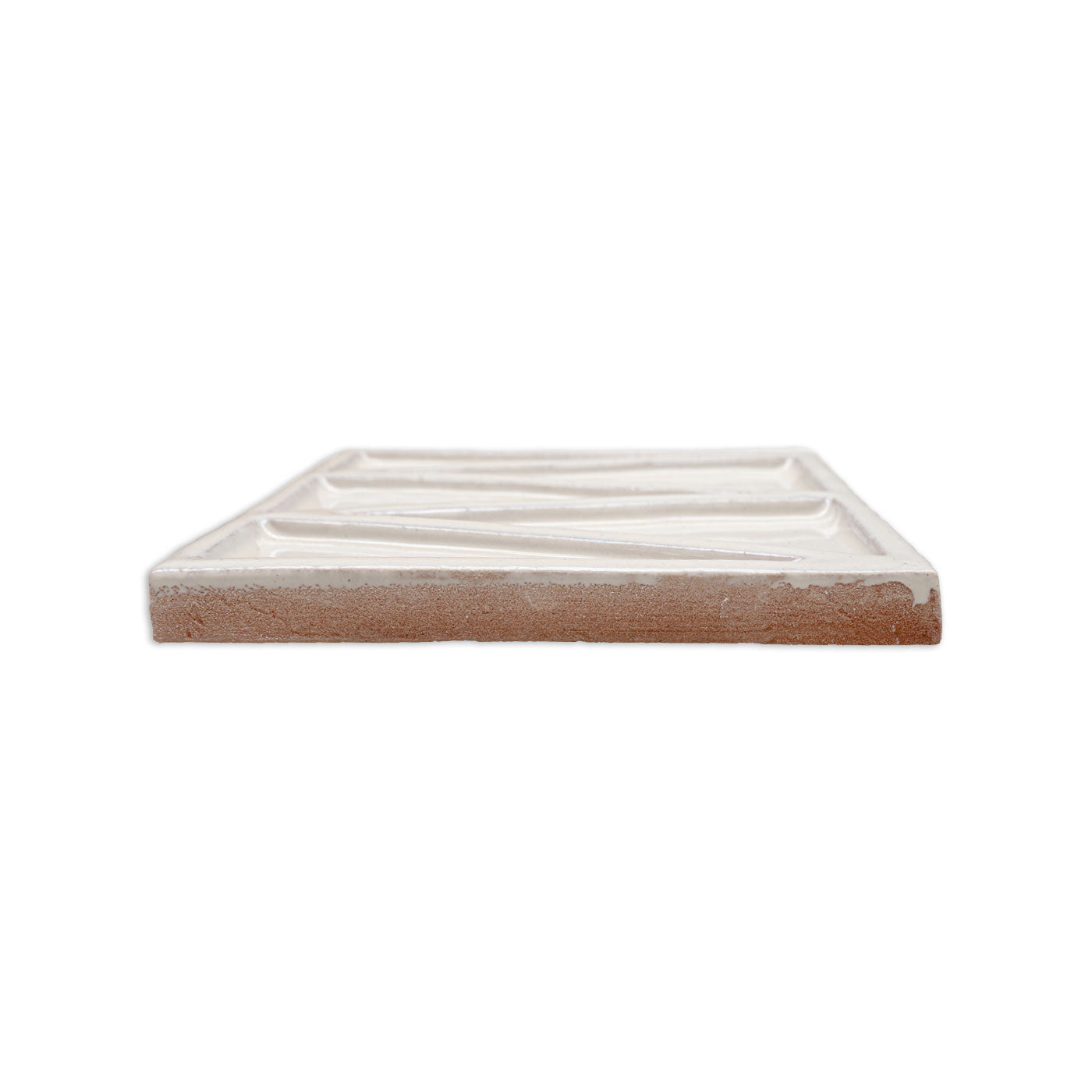 Solid tile in creamy off-white glaze by Clay Imports, showing a wavy textured surface and reddish-brown clay body from a side angle.