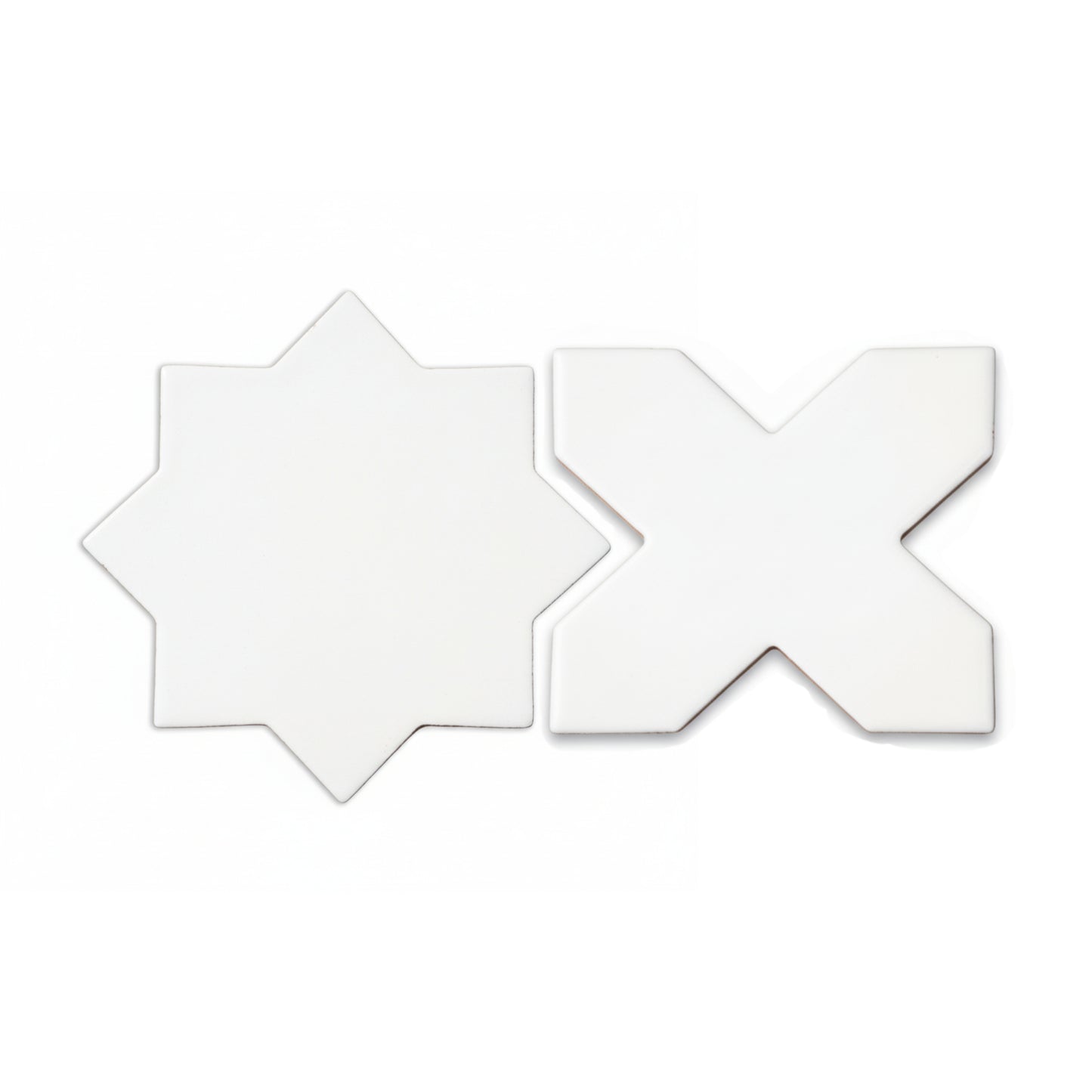 Two white star and cross shaped tiles by Clay Imports lying next to each other on a white background.