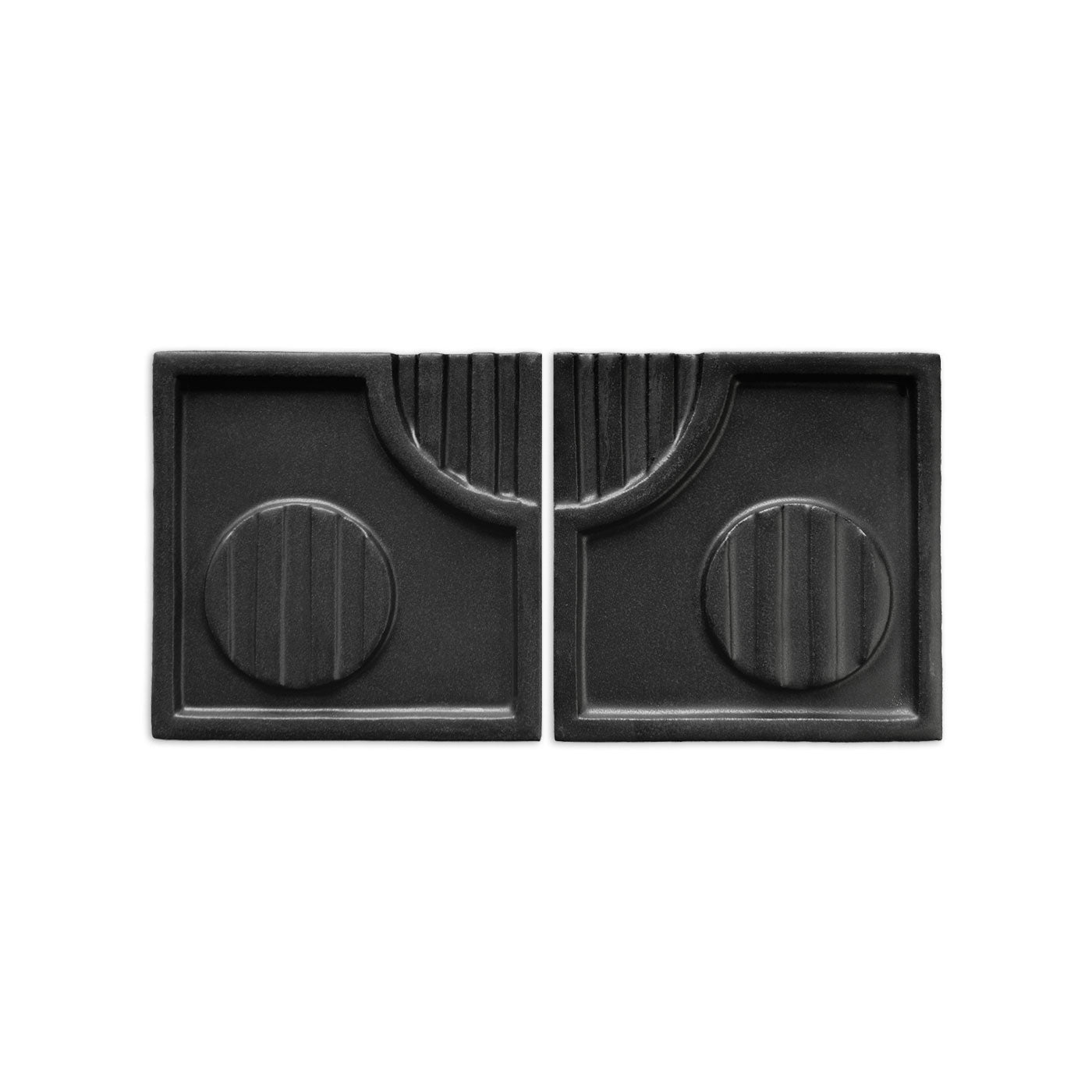 Black geometric decorative tiles by Clay Imports, featuring curved lines, vertical ridges, and circular motifs on a matte, textured surface, presented as a pair.