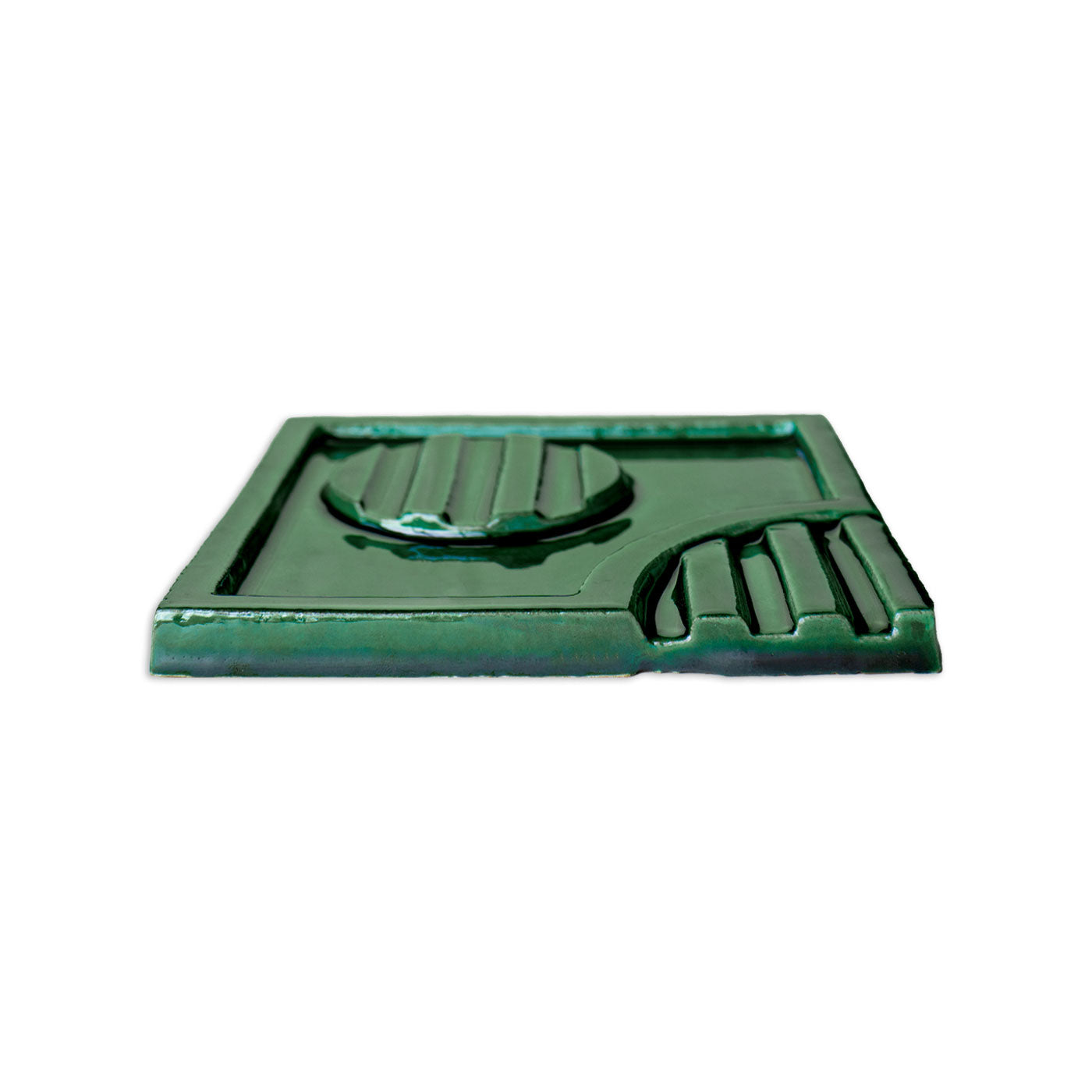 Deep green glossy decorative tile by Clay Imports, featuring a raised geometric relief pattern, shown from a low angle.