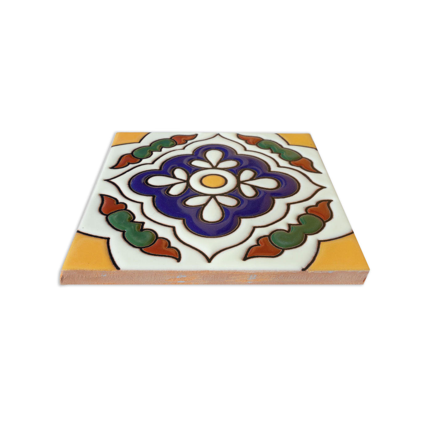White relief Talavera tile by Clay Imports with a dark blue floral center, yellow corners, and green-orange accents, seen at an angle.