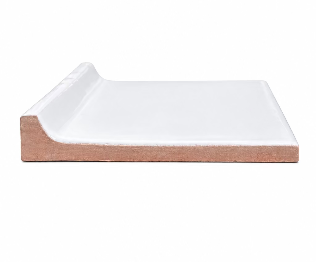 A single glossy white bullnose ceramic tile rests against a plain white background, showcasing its rounded edge and terracotta body.