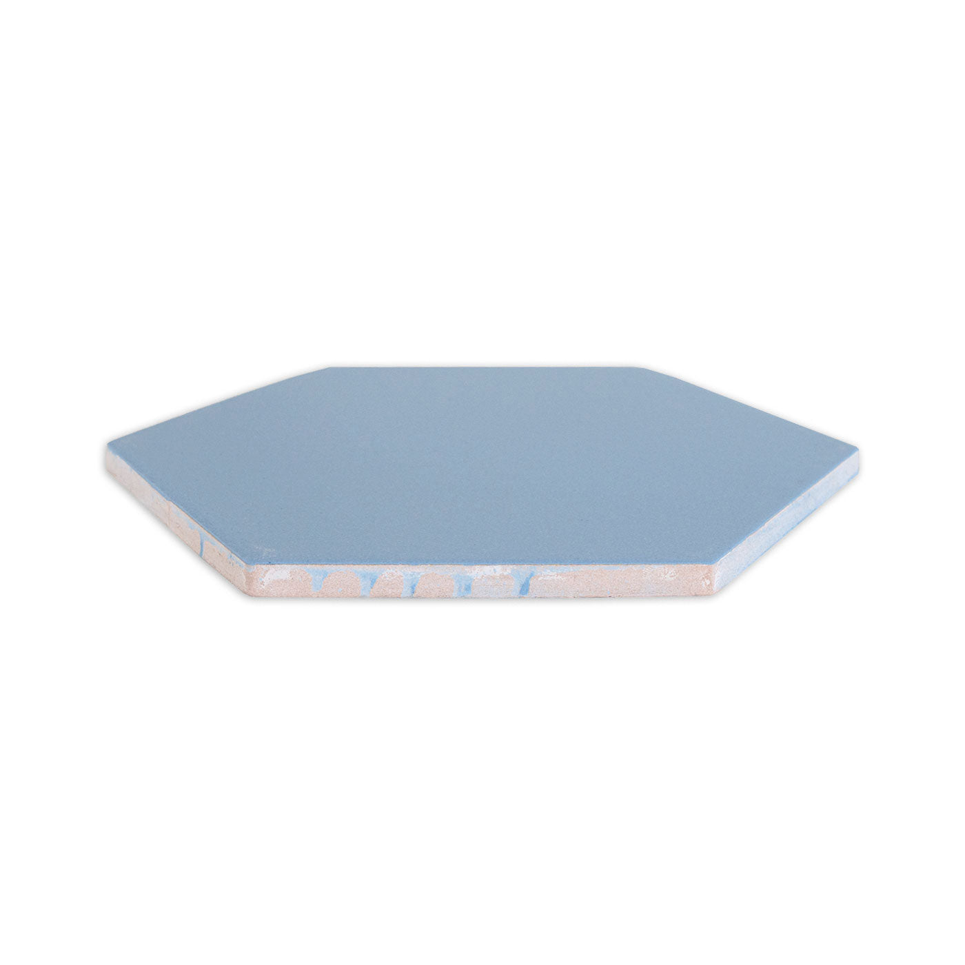 A blue hexagon clay tile by Clay Imports, shown from the side, revealing its rough textured edge.