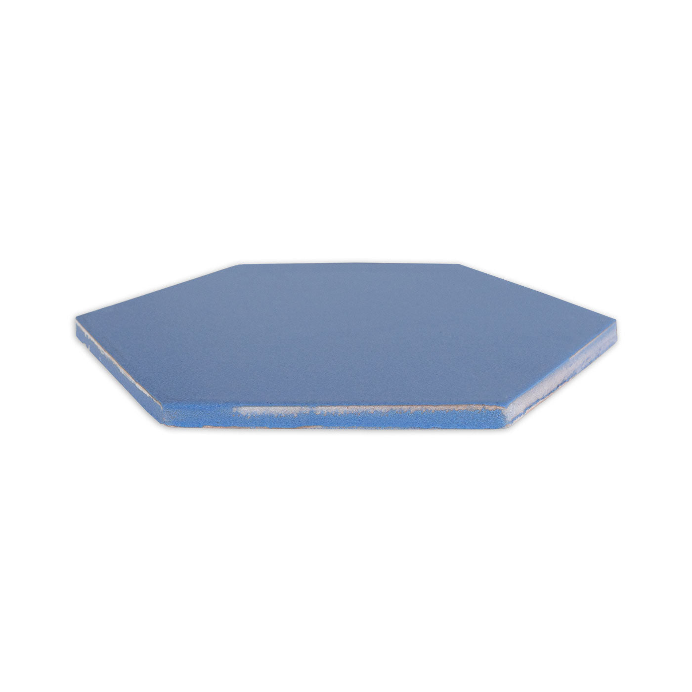 A blue hexagon clay tile by Clay Imports with rough, light-colored edges, viewed from a slight angle.