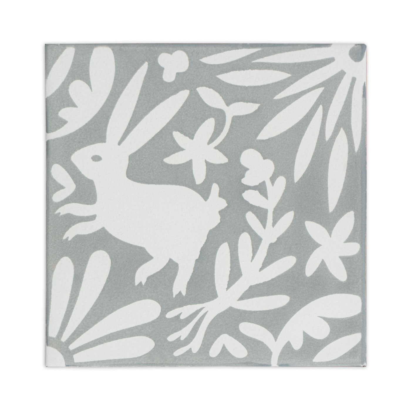 White and grey sample tile by Clay Imports with a whimsical rabbit and floral pattern.