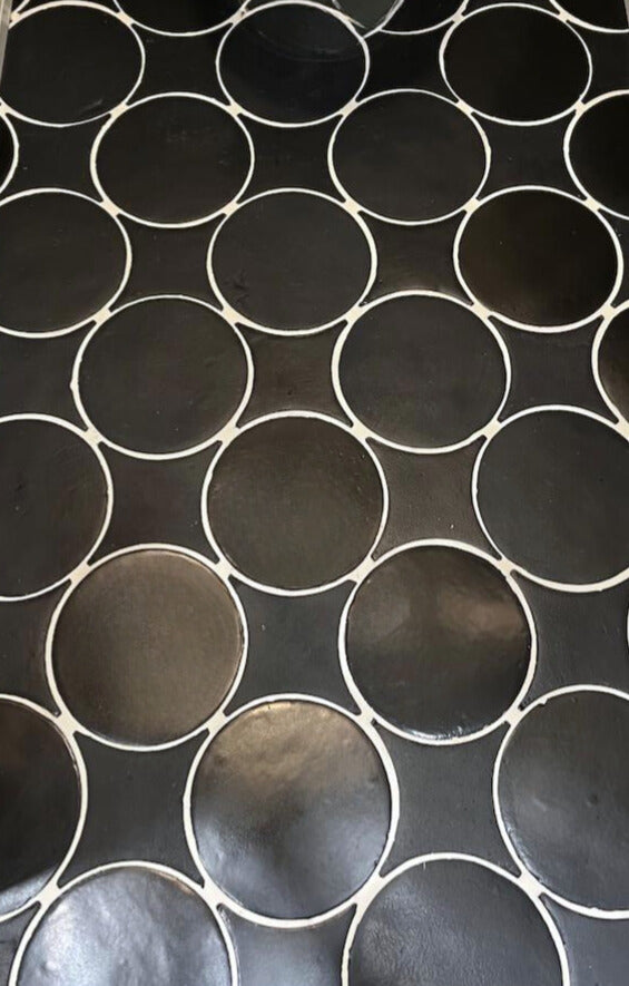 Black suede circular tile by Clay Imports with contrasting white grout lines.