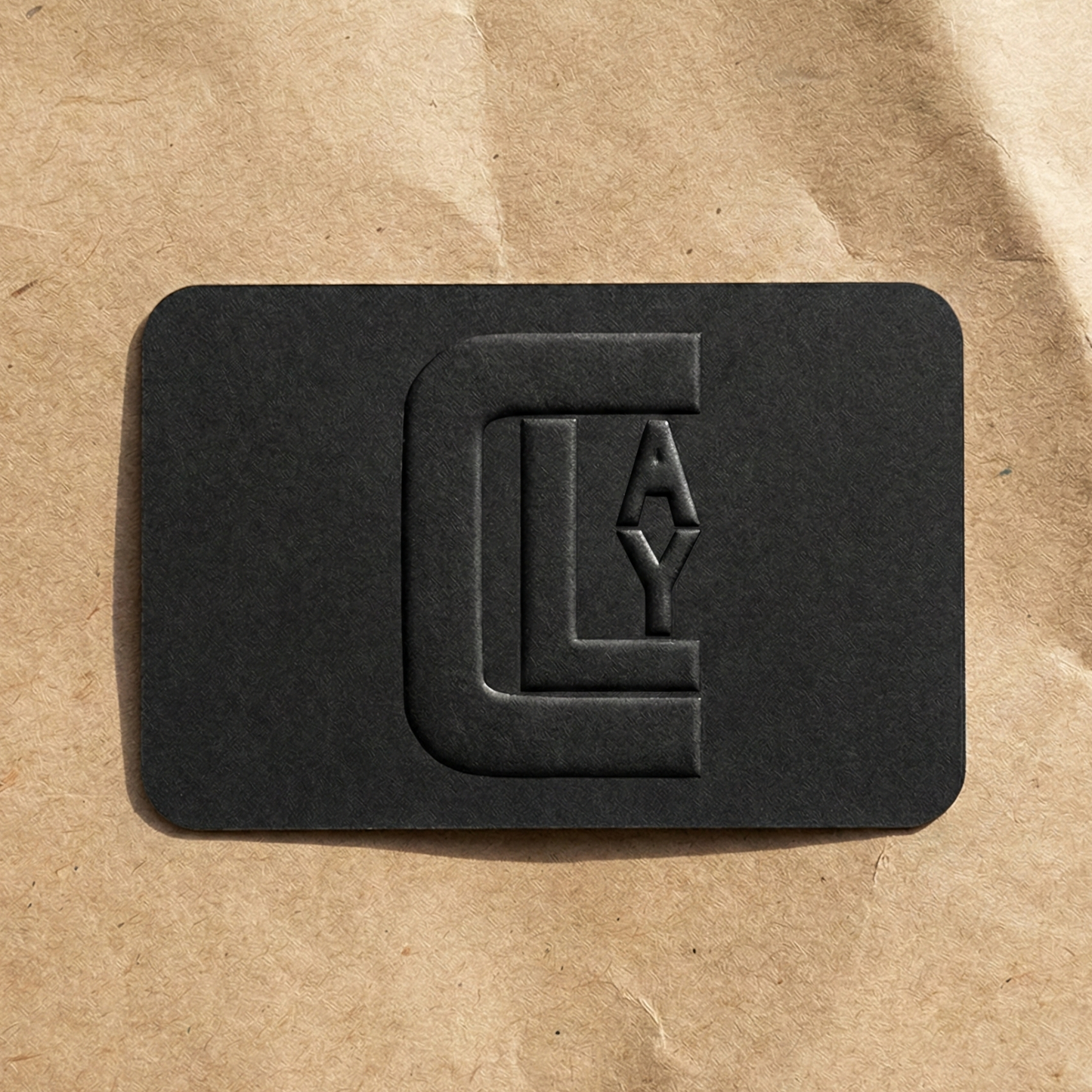Black textured gift card from Clay Imports, featuring an embossed CLAY logo design on a brown paper surface.