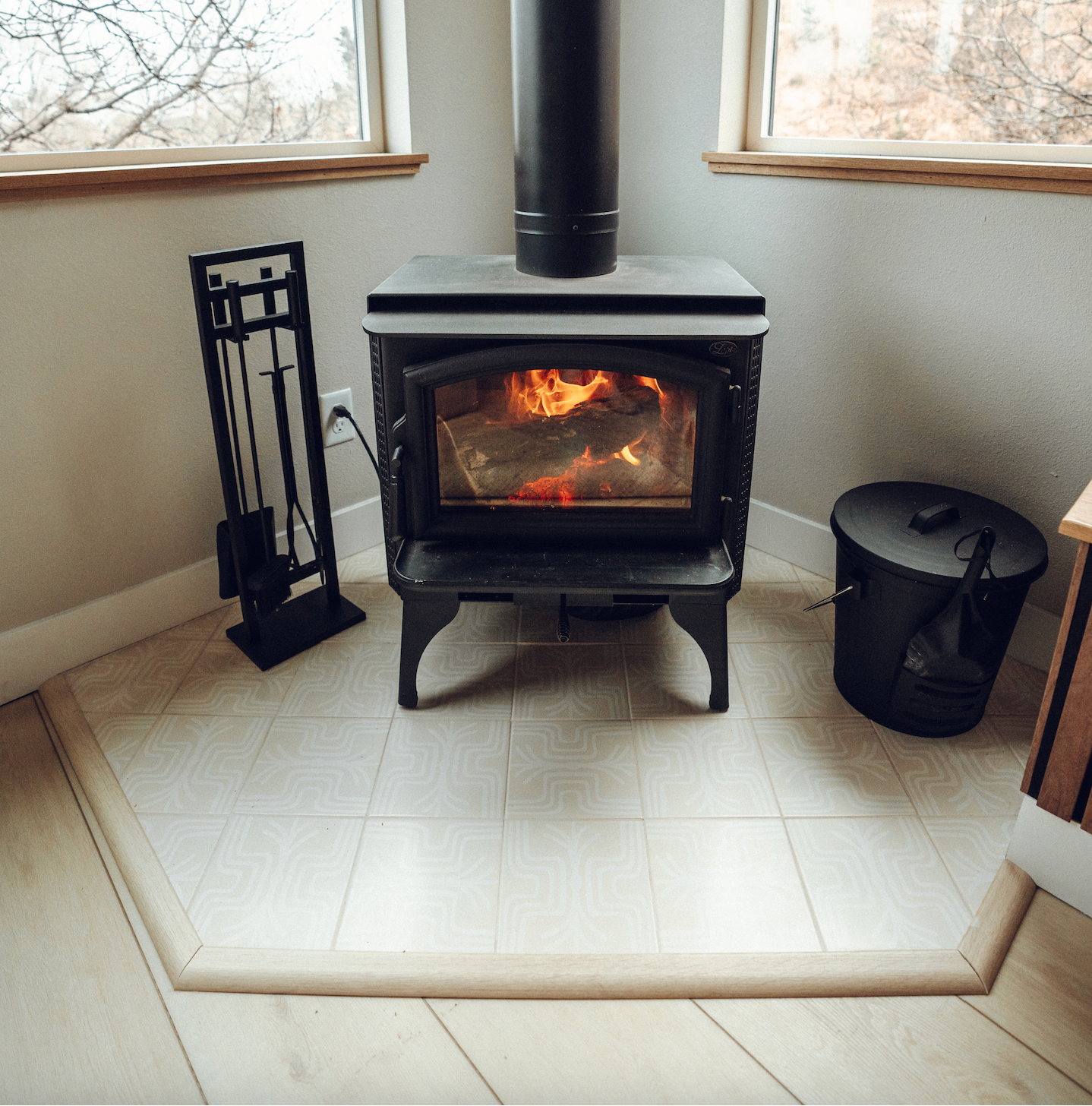 White 8x8 Fringe Dew patterned tiles by Clay Imports on a floor around a black wood stove.