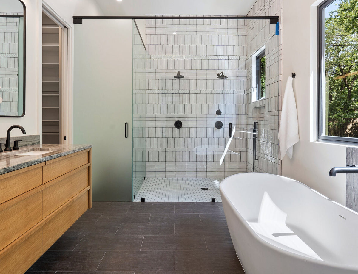 Glazed thin brick in Perla Gloss finish by Clay Imports, 2.5x8 size, installed vertically in a modern shower with dark grout.