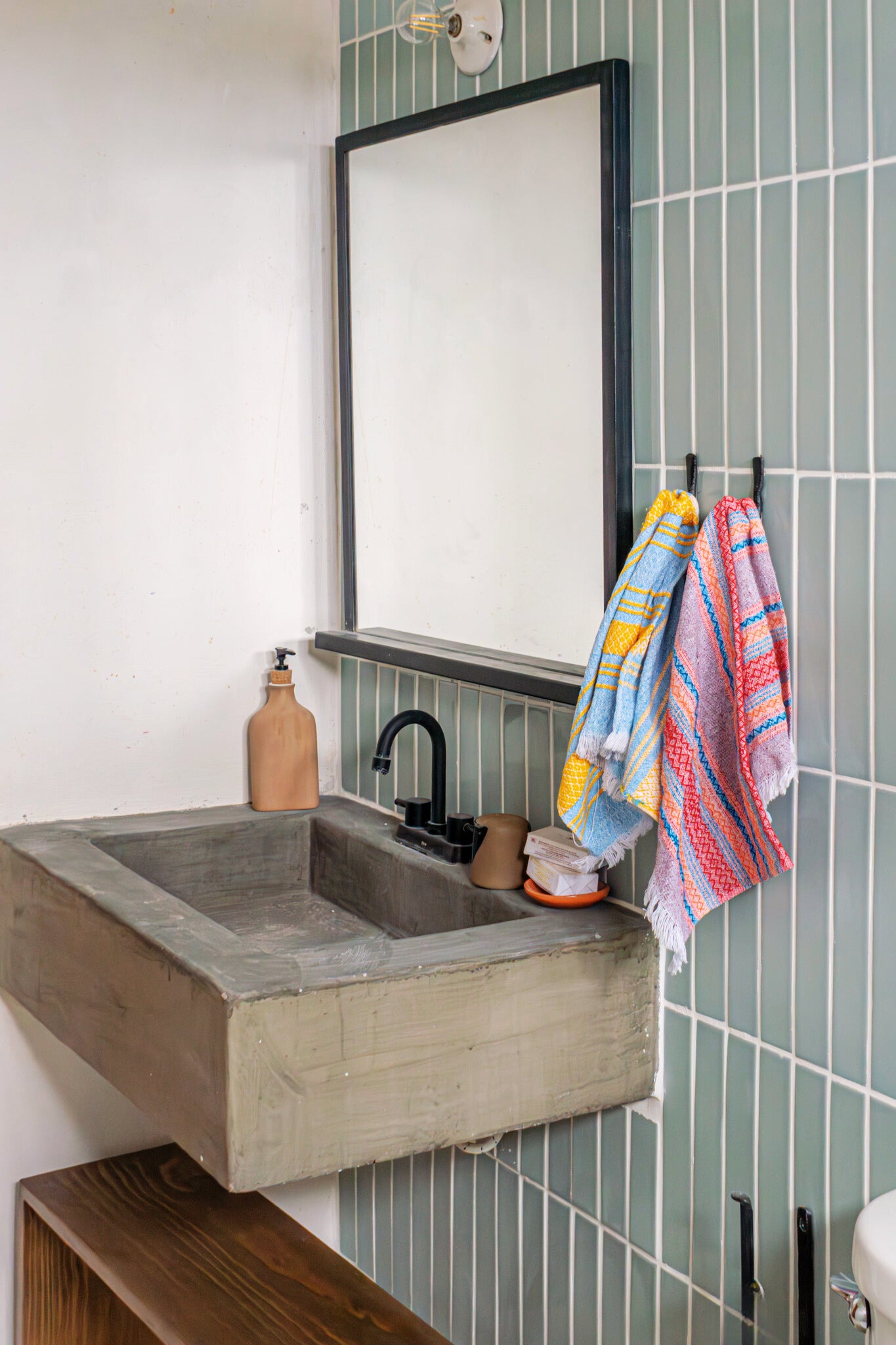 Glossy sage green 2x12 solid tiles by Clay Imports, vertically stacked with white grout on a modern bathroom wall.