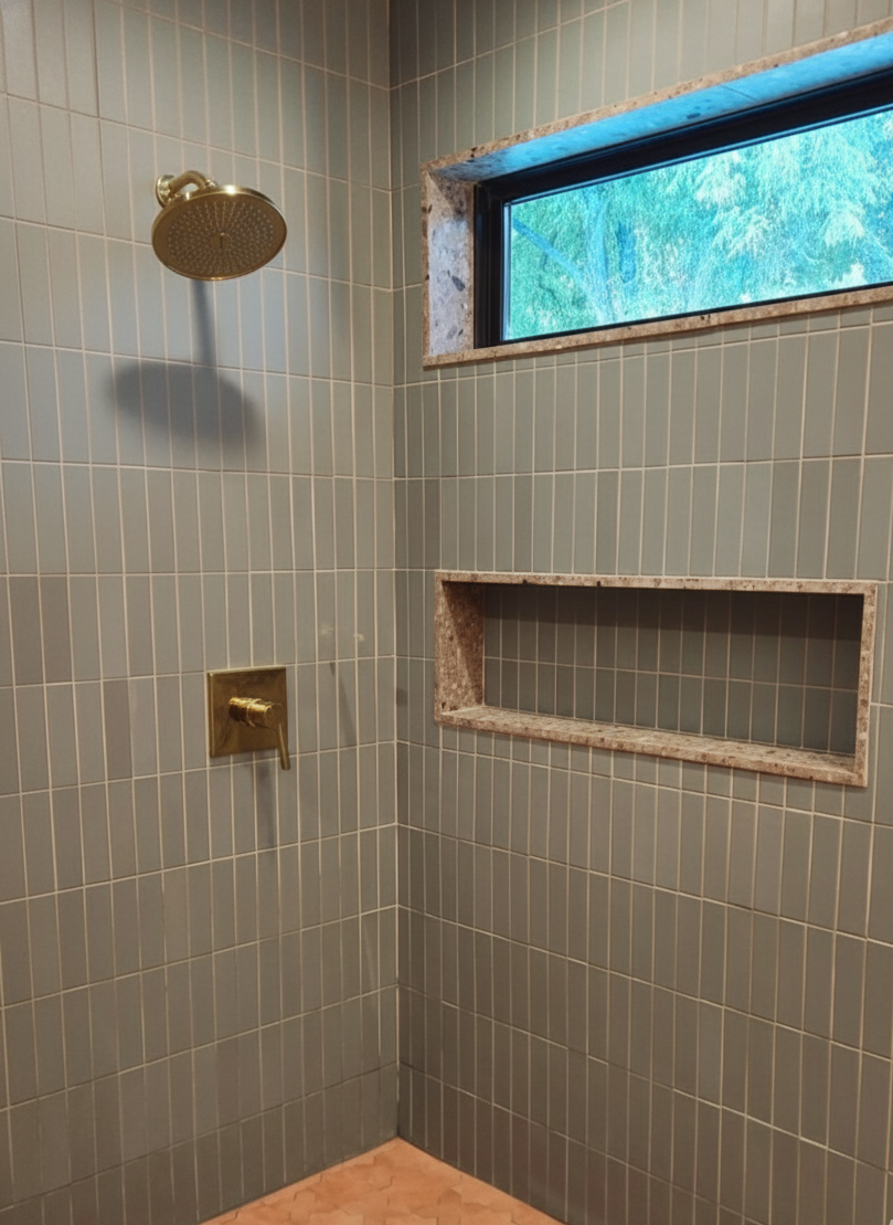 Green vertical clay tiles by Clay Imports in a modern shower with brass fixtures and a window.