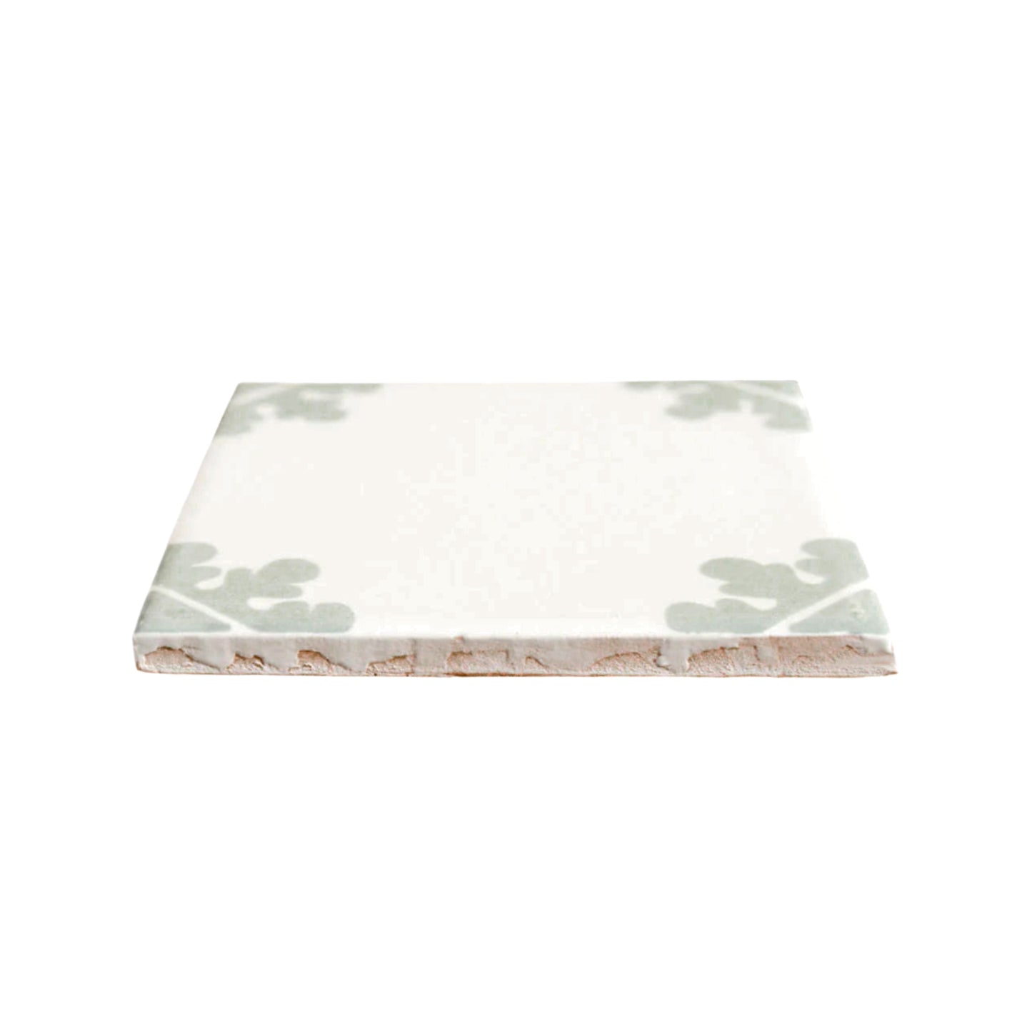 Cream traditional Talavera tile with green corner leaf pattern by Clay Imports Handmade Tile, shown from a low angle revealing its textured clay base.