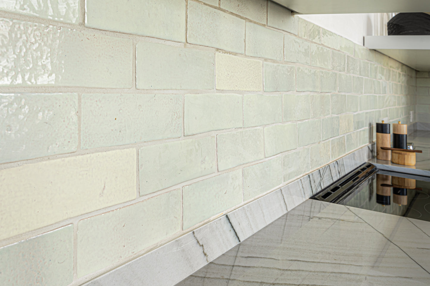 Glazed Thin Brick Tonic 2.5x8 by Clay Imports, featuring a pale green, textured surface as a kitchen backsplash.
