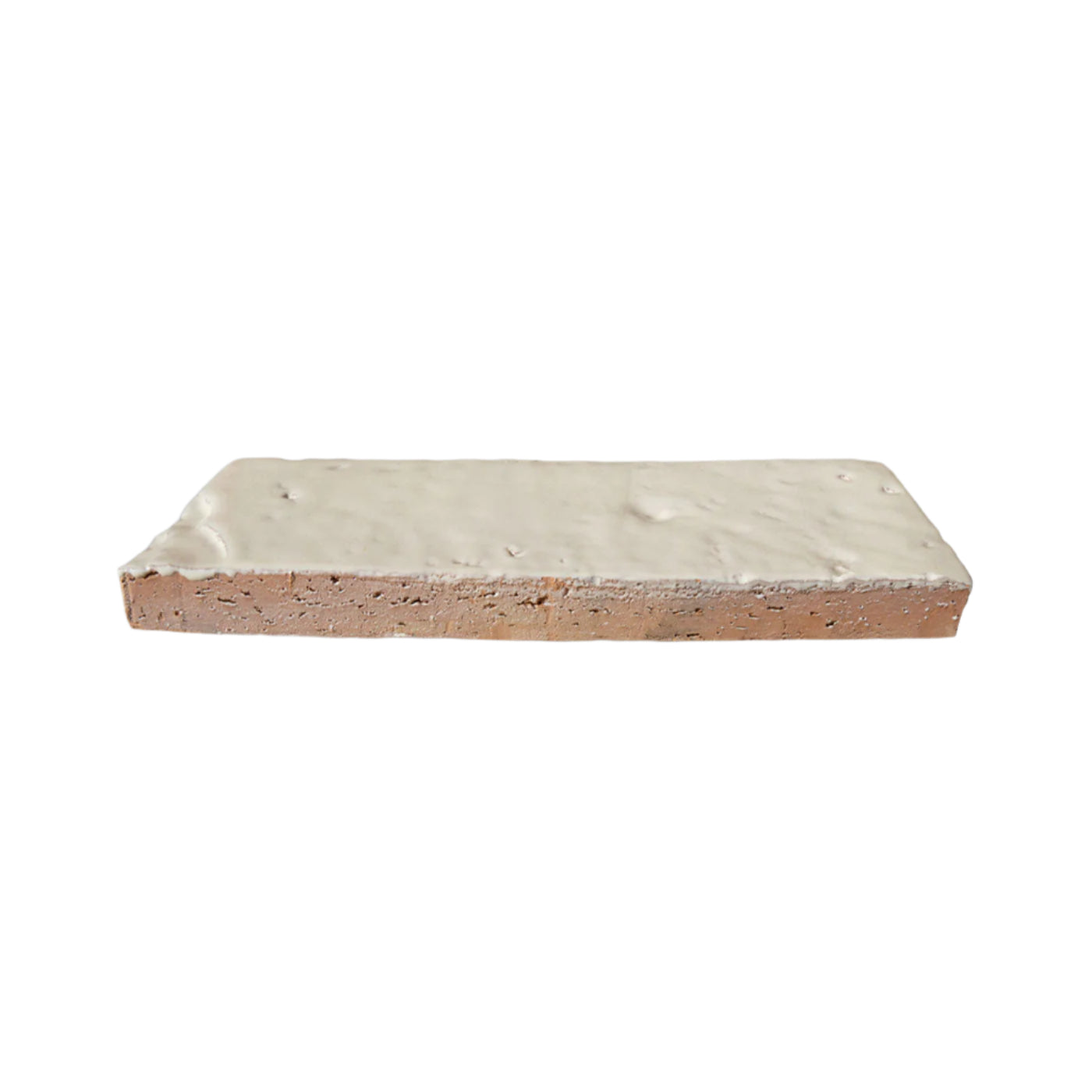 Glazed thin brick in Tupelo Blanco by Clay Imports, featuring a light off-white top and a reddish-brown porous cut edge.