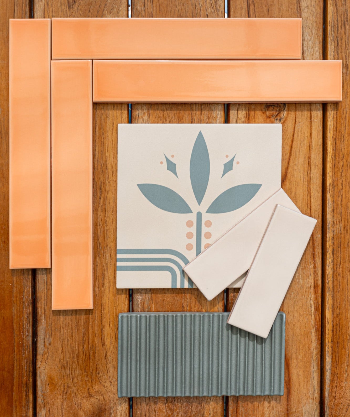 Assorted tile samples by Clay Imports, featuring orange, patterned blue, smooth beige, and ridged gray tiles on wood.