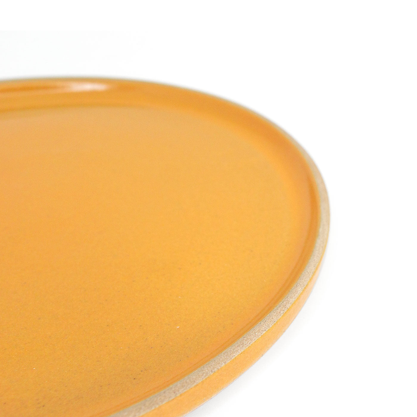 Orange glazed clay snack plate by Clay Imports with a natural unglazed rim, shown at an angle.