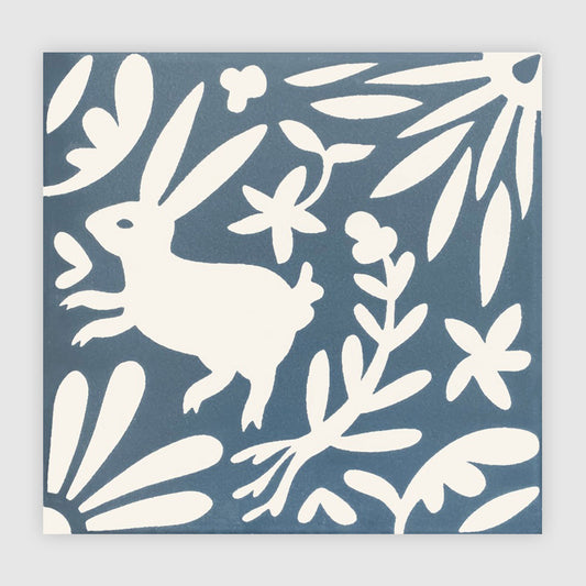 Whimsical white rabbit and blooming floral design on a dark blue decorative tile.