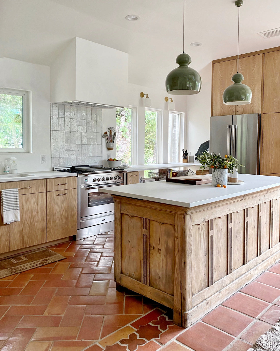 Warm Austin kitchen with terracotta Saltillo tile floors, wooden island, and green pendant lights.