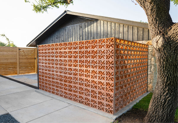 Breeze block wall in front of house with concrete driveway and wooden fence clay imports