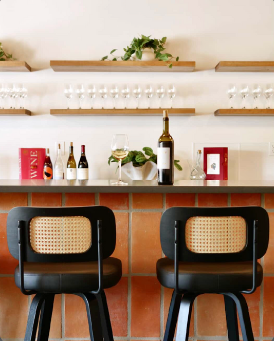 A modern wine bar showcases organic terracotta tiles on its base, paired with stylish black cane stools and wine displays.