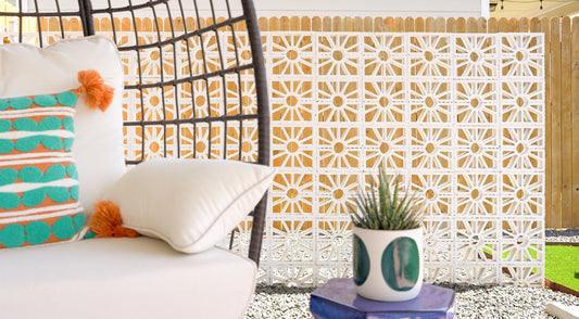 Vibrant white painted breeze blocks create a decorative wall on a relaxed patio with a hanging chair.