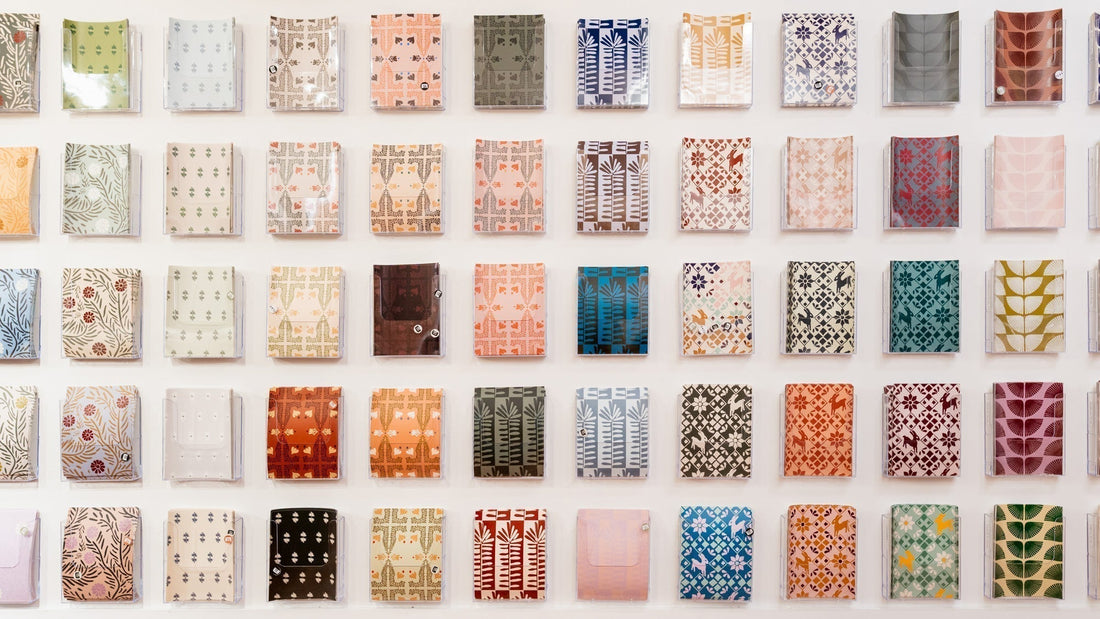 A grid of diverse patterned design samples on a white wall, featuring floral, geometric, and folk motifs, ideal for tile or wallpaper inspiration.
