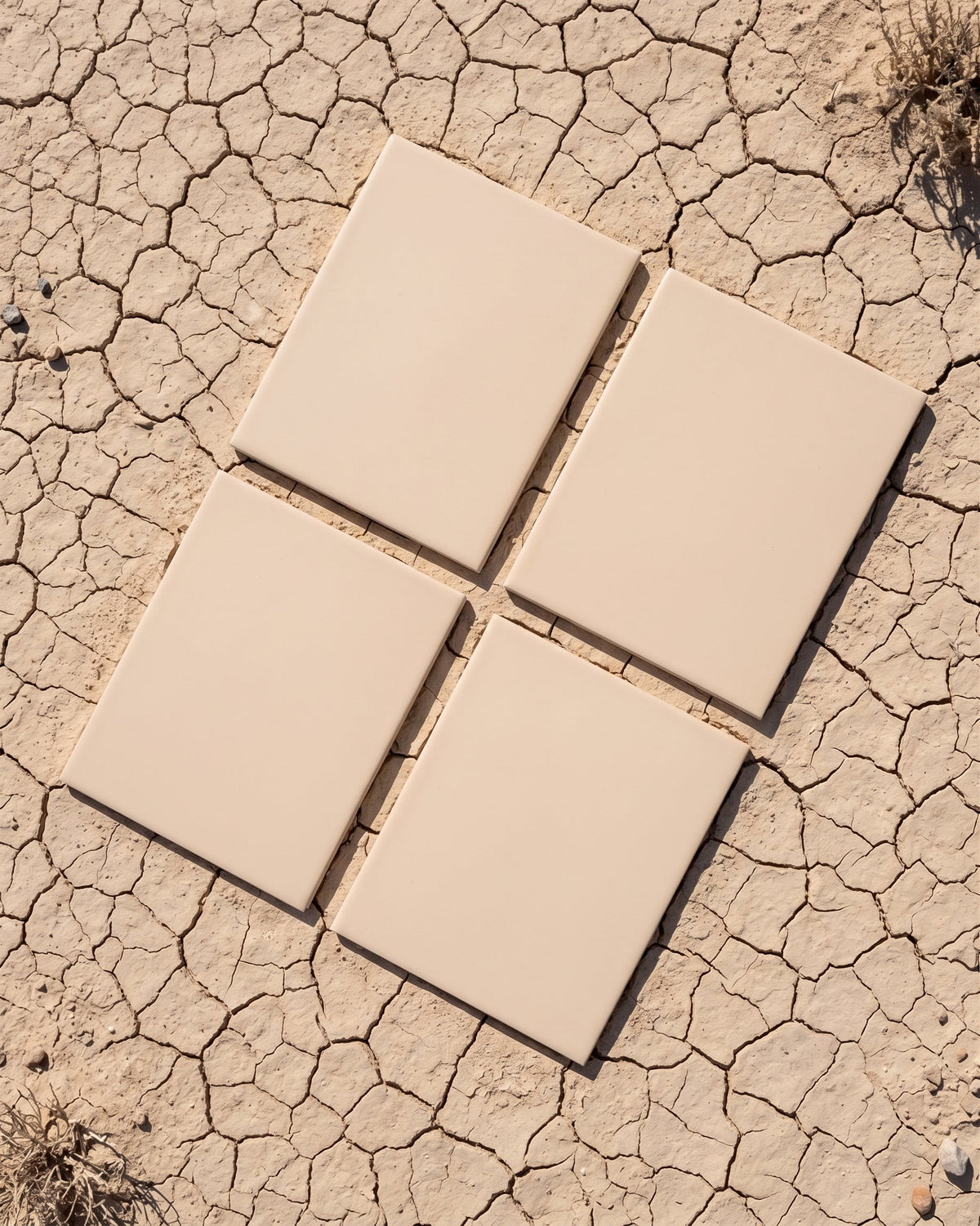 Four light beige matte solid tiles by Clay Imports, arranged in an overlapping column on a textured white surface.