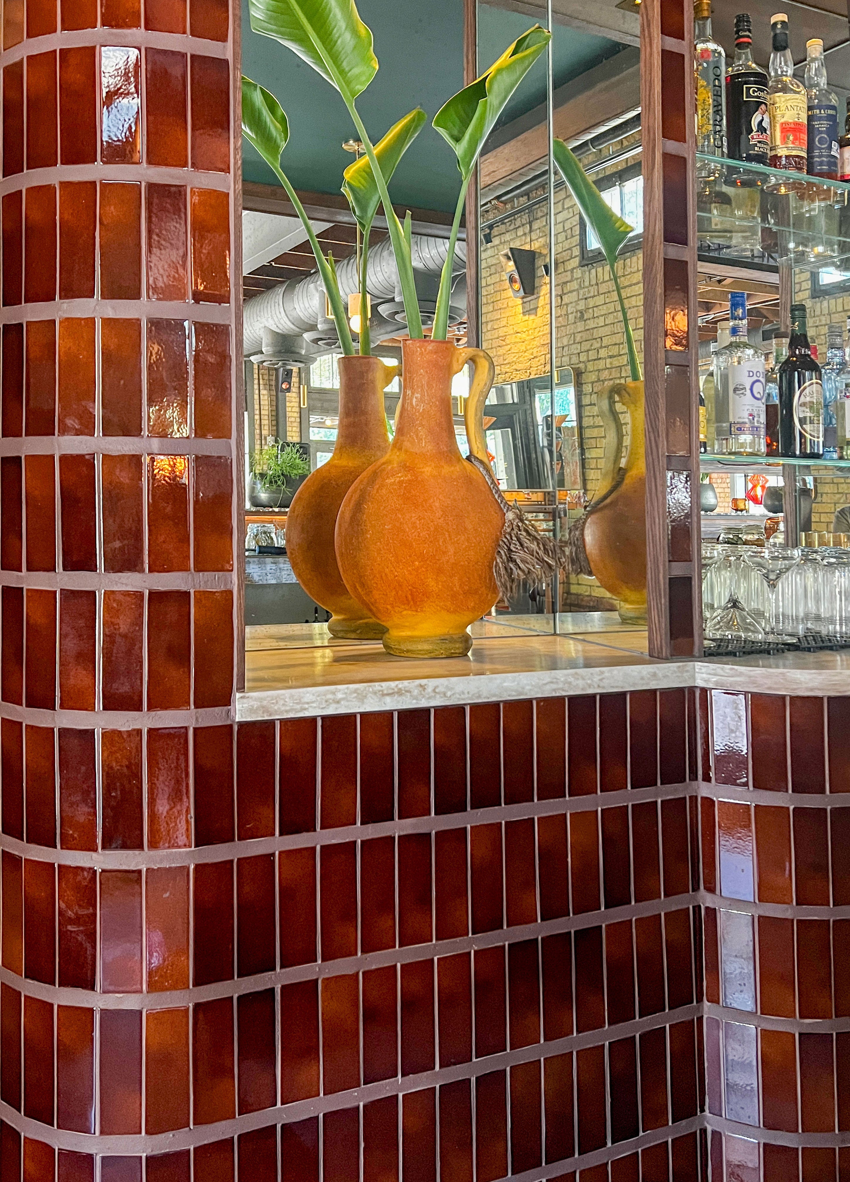 Warm, glossy root beer-toned tiles and vintage bar reflections for sophisticated home entertaining.
