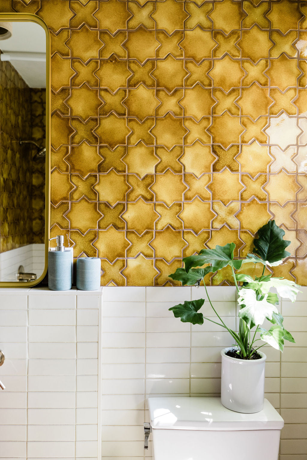 Warm nectar crackle star pattern tiles and clean white subway tiles adorn a retro-inspired bathroom with lush greenery.