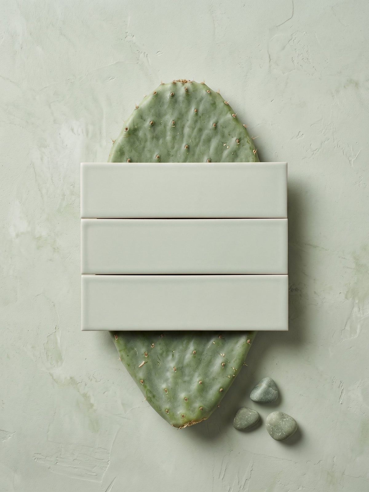 Light green matte rectangular solid tile by Espadin, installed in shower corner with white grout, gold linear drain, and beige waffle towels on wooden stool.