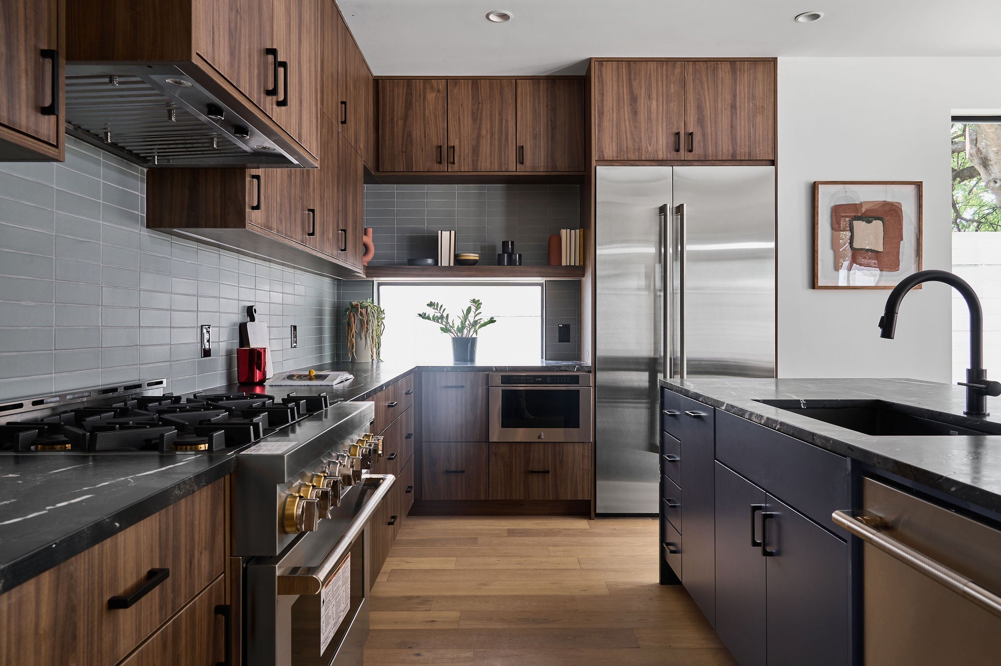 A sophisticated Agave kitchen design showcasing rich walnut cabinetry, dark marble, and sleek gray tiles for a contemporary, natural feel.