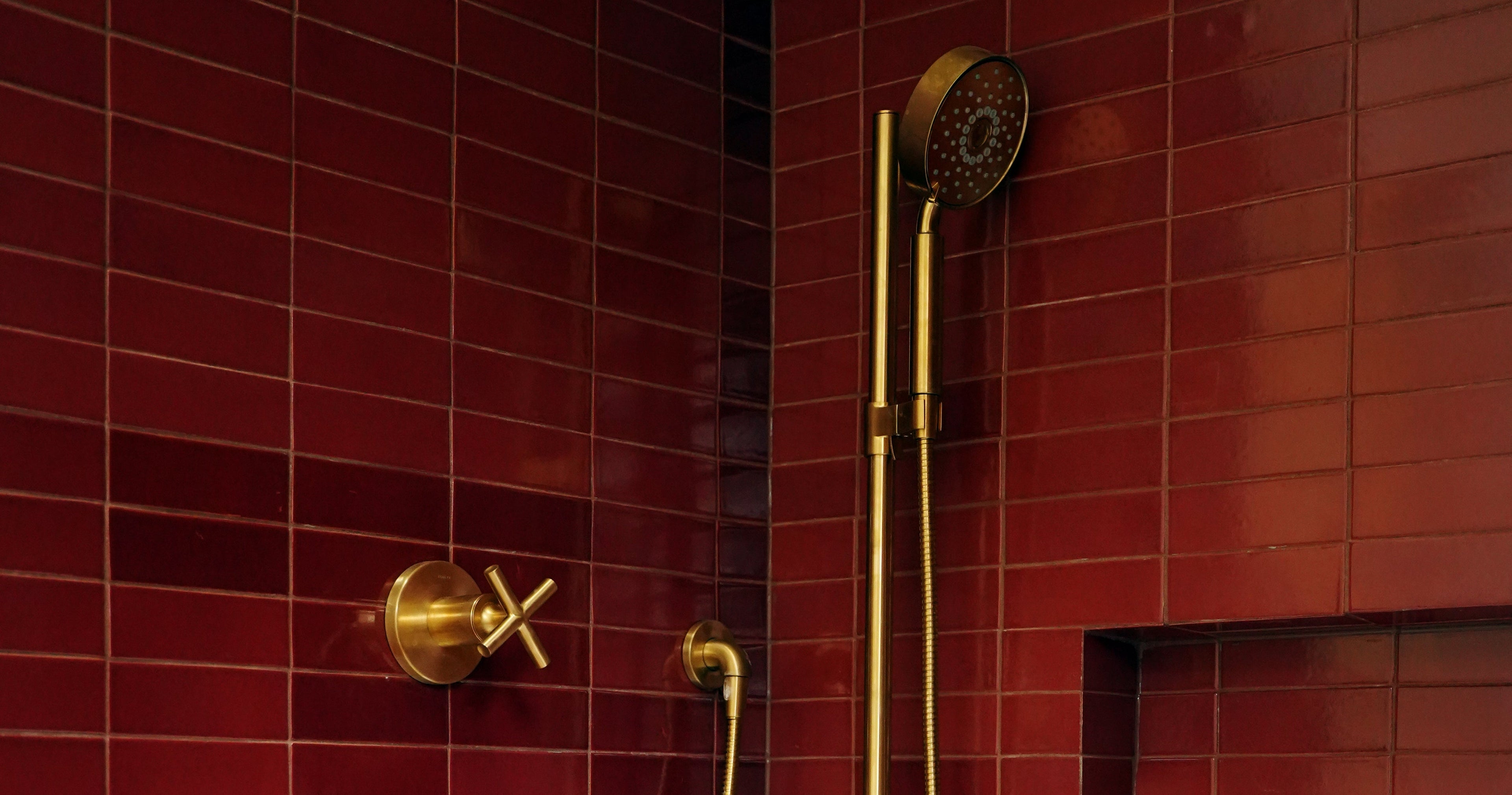 Chic bathroom featuring deep plum subway tiles and elegant brushed brass shower fixtures.