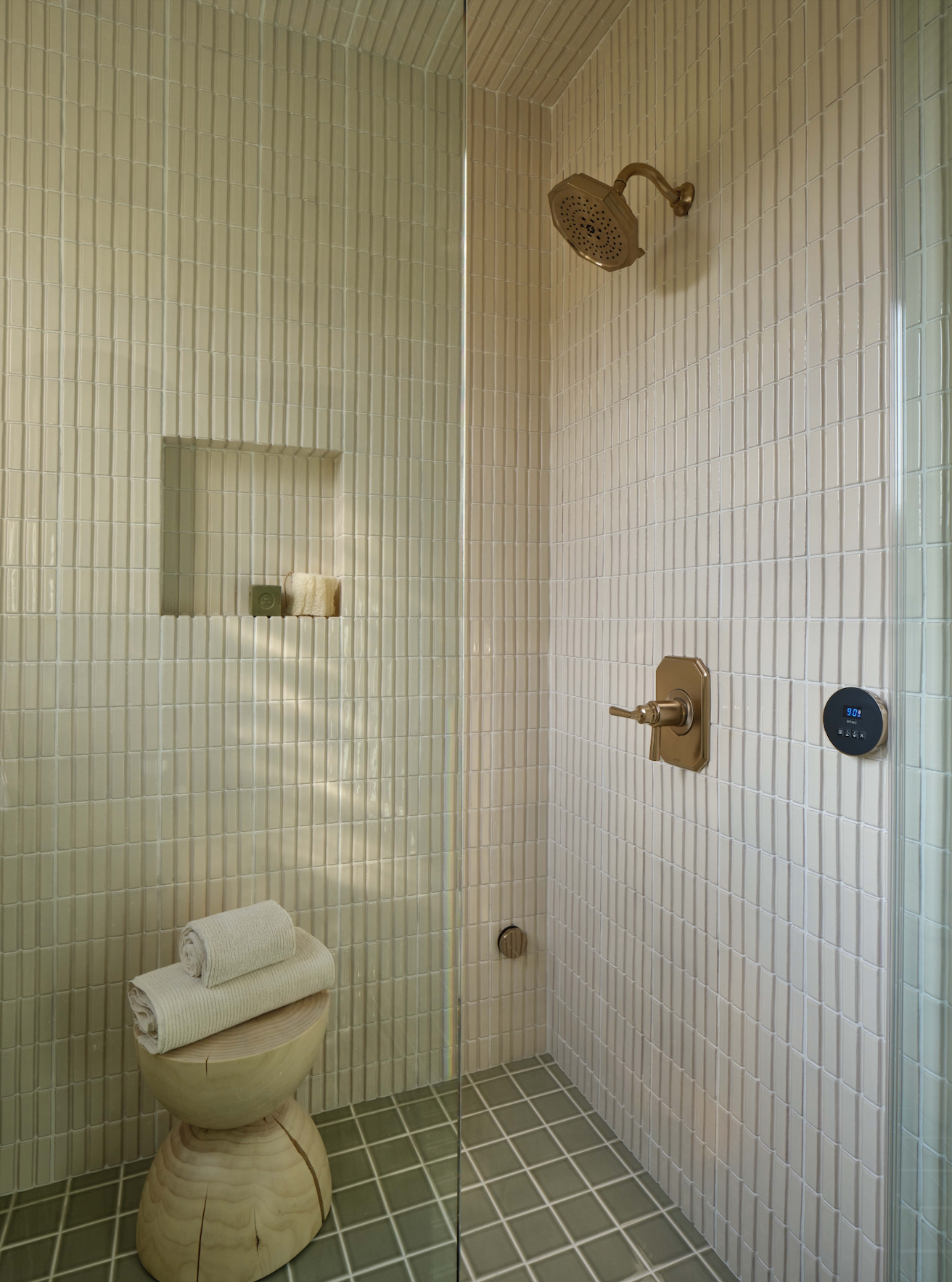 Relaxing shower showcasing light green vertical and square tiles, accented with modern brass fixtures, embodying a fresh, tranquil design.