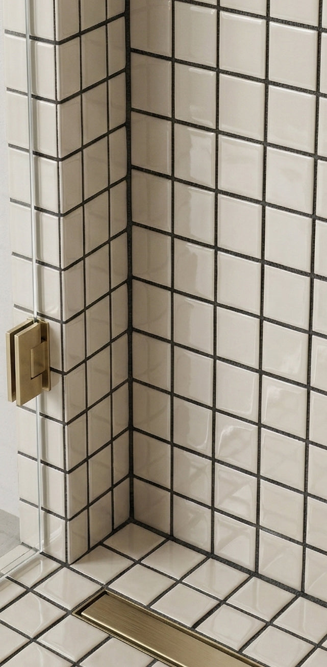 Cream square clay tiles by Clay Imports with dark grout, a brass linear drain, and a shower door hinge in a modern shower corner.